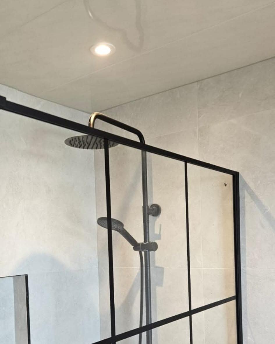 Black-framed grid shower screen with a matt black rainfall shower