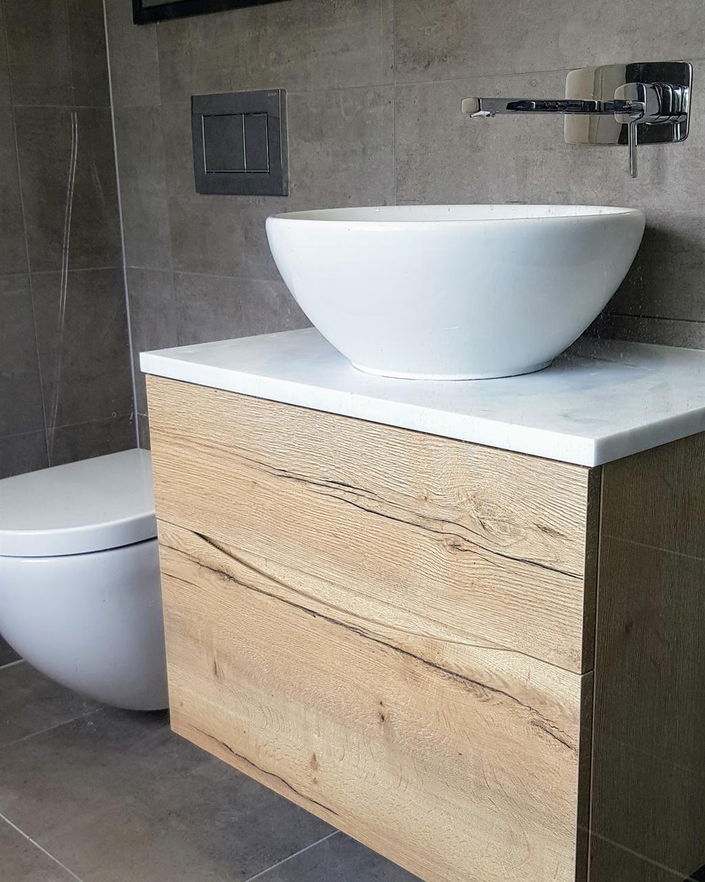Oak-effect wall-hung vanity with a white vessel basin and wall-mounted tap